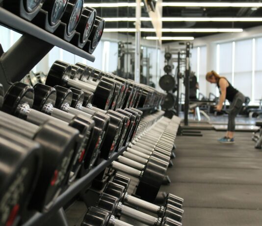 피트니스 목표 달성을 위한 식사와 운동의 조화 woman standing surrounded by exercise equipment