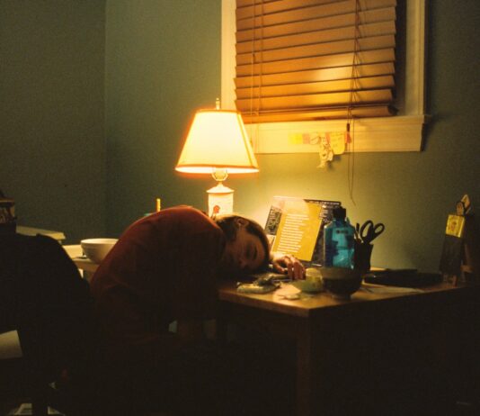 만성피로, 단순한 피로가 아닌 신호… 원인과 극복 방법은? a person sitting at a desk in front of a lamp