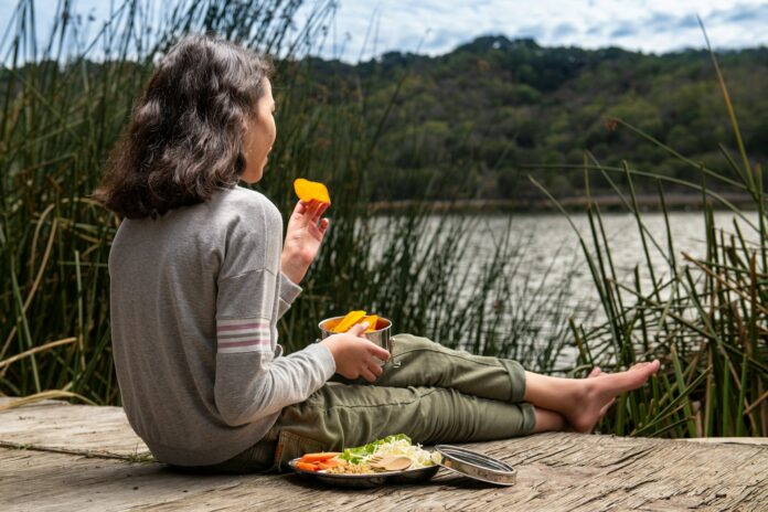 Photo by Sandra Harris woman in gray long sleeve shirt sitting on brown wooden dock during daytime