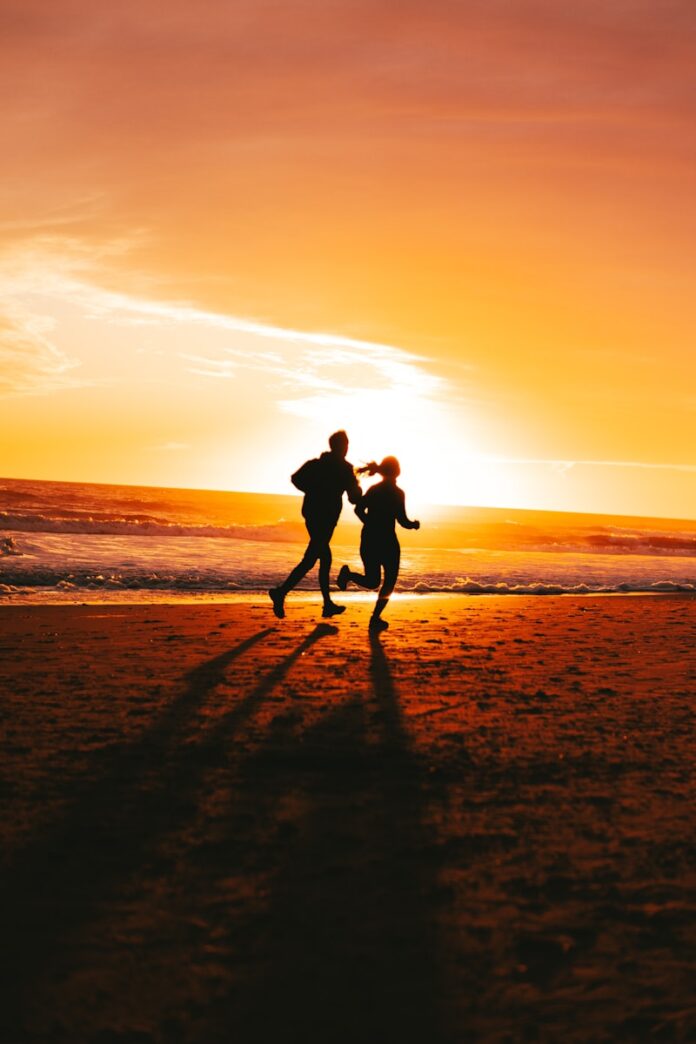 Photo by Esteban Bonilla a couple of people running on a beach at sunset