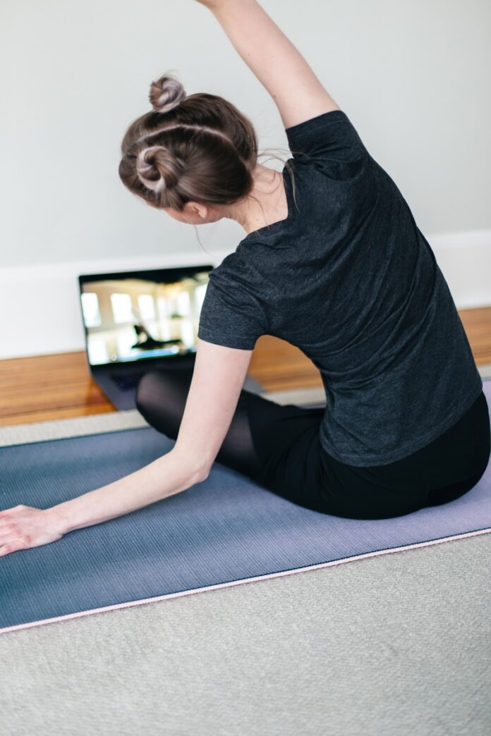 Photo by Kari Shea woman in black t-shirt and black pants lying on black yoga mat