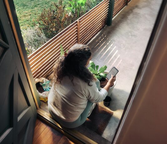 만성피로, 일상에서 벗어나는 실천법은? Woman sitting on balcony with smartphone